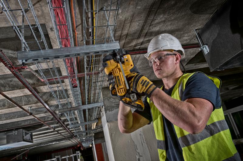 Worker using DEWALT DCS350NT tool to cut metal conduit on ceiling installation site.